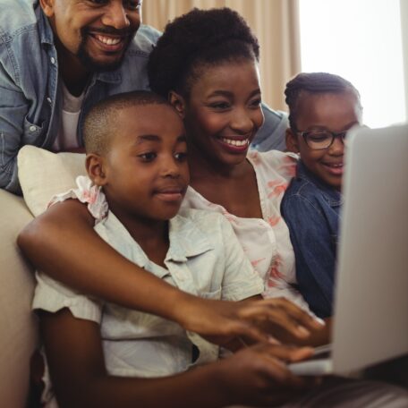 Parents and kids using laptop in living room