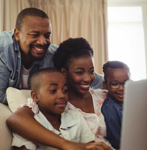 Parents and kids using laptop in living room