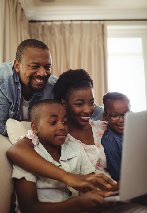 Parents and kids using laptop in living room